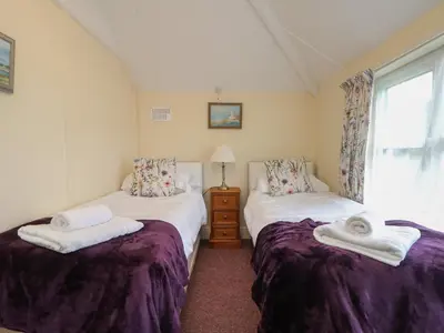 two twin beds in a room with a window at 4 Rose Cottages in Looe