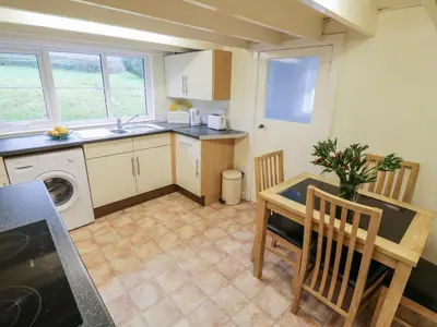 a kitchen with a table and a sink and a table and chairs at 4 Rose Cottages in Looe