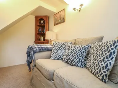 a living room with a couch with blue and white pillows at 4 Rose Cottages in Looe