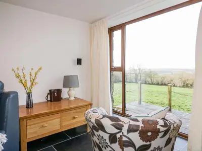 a living room with a chair and a window at Sleepy Fox in Bodmin