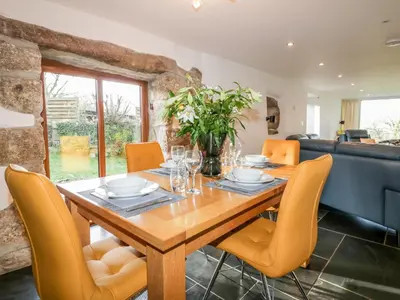 a dining room with a wooden table and yellow chairs at Sleepy Fox in Bodmin
