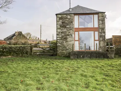 a stone house with a window in a field at Sleepy Fox in Bodmin