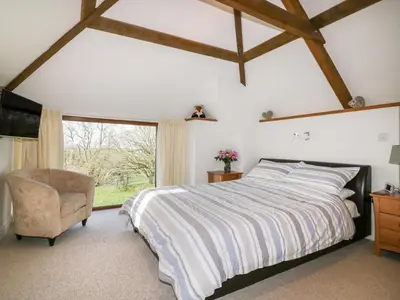 a bedroom with a bed and a chair and a window at Sleepy Fox in Bodmin