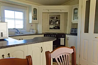 a kitchen with white cabinets and a sink and a stove at Coosewartha Countryside Holiday Rental in Truro