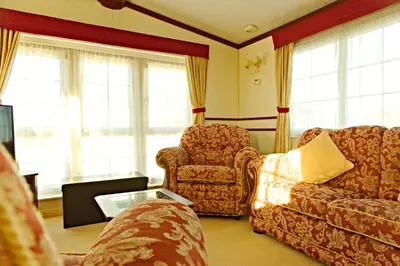 a living room with a couch and a chair and windows at Coosewartha Countryside Holiday Rental in Truro