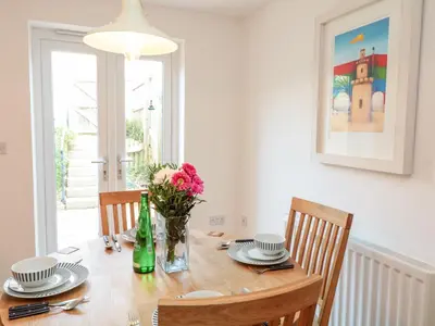 a dining room table with a vase of flowers on it at Ripple in Bodmin