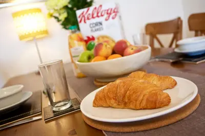 a table with a plate of bread and a bowl of fruit at Compass Point in Carbis Bay