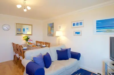 a living room with a table and a white couch at Compass Point in Carbis Bay