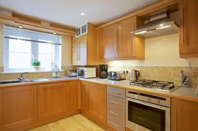 a kitchen with wooden cabinets and a stove top oven at Compass Point in Carbis Bay