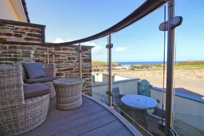 a balcony with a couch and a table on a deck at BY THE BEACH, The Quies, Beach House in St Merryn