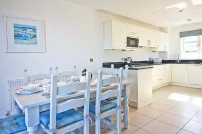 a kitchen and dining room with a table and chairs at BY THE BEACH, The Quies, Beach House in St Merryn