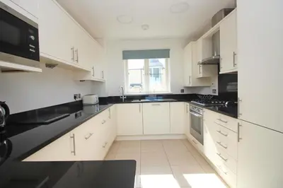 a kitchen with white cabinets and black counter tops at BY THE BEACH, The Quies, Beach House in St Merryn