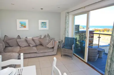 a living room with a couch and a balcony at BY THE BEACH, The Quies, Beach House in St Merryn