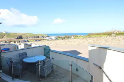 a balcony with a table and a view of the beach at BY THE BEACH, The Quies, Beach House in St Merryn