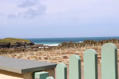 a bench on the beach with a fence and the ocean at APARTMENT BY THE BEACH, courtyard garden in St Merryn