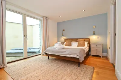 a bedroom with a bed and a large window at APARTMENT BY THE BEACH, courtyard garden in St Merryn