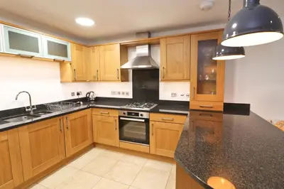 a kitchen with wooden cabinets and a black counter top at APARTMENT BY THE BEACH, courtyard garden in St Merryn
