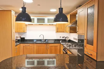 a kitchen with wooden cabinets and black counter tops at APARTMENT BY THE BEACH, courtyard garden in St Merryn