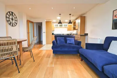 a living room with a blue couch and a table at APARTMENT BY THE BEACH, courtyard garden in St Merryn