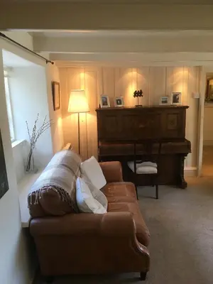 a living room with a couch and a piano at The Thatched Cottage in Truro