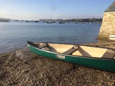 a green boat on the shore of a body of water at The Thatched Cottage in Truro