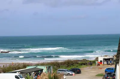 a view of the ocean with cars parked on the beach at STYLISH, BEACHSIDE apartment, sea views in St Merryn