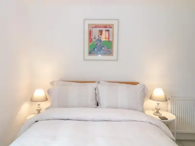 a bedroom with a white bed with two lamps at 1 Jubilee Cottage in Tintagel