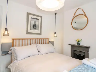 a bedroom with a bed and a mirror at 1 Jubilee Cottage in Tintagel