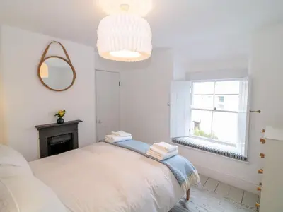 a white bedroom with a bed and a window at 1 Jubilee Cottage in Tintagel