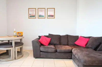 a living room with a brown couch with pink pillows at SEA VIEWS, beachside apartment with balcony in St Merryn
