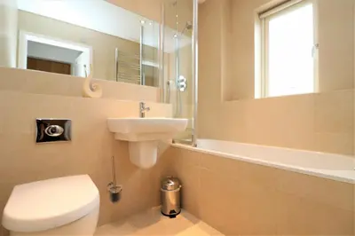 a bathroom with a toilet and a sink and a mirror at SEA VIEWS, beachside apartment with balcony in St Merryn