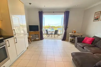 a living room with a couch and a television at SEA VIEWS, beachside apartment with balcony in St Merryn