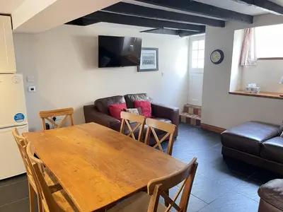 a living room with a table and a couch at Hollies Cottage in St Ives