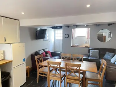 a kitchen and living room with a table and a couch at Hollies Cottage in St Ives