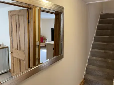 a mirror on a wall next to a staircase at Hollies Cottage in St Ives