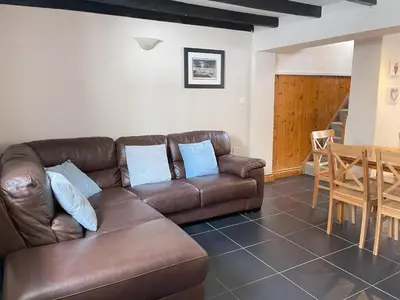 a living room with a brown couch and a table at Hollies Cottage in St Ives
