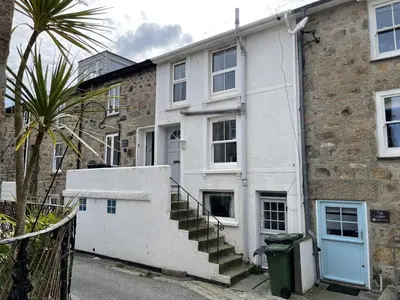 a white building with stairs in front of it at Hollies Cottage in St Ives