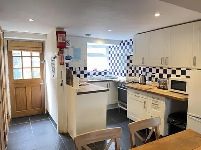 a kitchen with white cabinets and black and white tiles at Hollies Cottage in St Ives