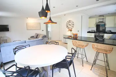 a kitchen and living room with a white table and chairs at CLOSE TO BEACH, dogs welcome, private garden in St Merryn