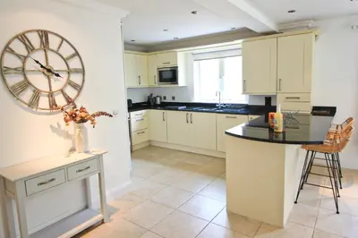 a kitchen with a large clock on the wall at CLOSE TO BEACH, dogs welcome, private garden in St Merryn