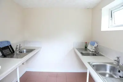 a white bathroom with two sinks and a window at Tehidy Holiday Park Wigwam Camping Cabins in Illogan