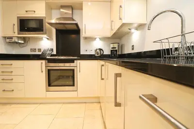 a kitchen with white cabinets and black counter tops at APARTMENT BY THE BEACH The Foxcove in St Merryn