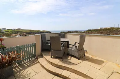 a patio with a table and chairs on a balcony at APARTMENT BY THE BEACH The Foxcove in St Merryn