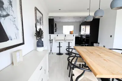 a kitchen and dining room with a wooden table and chairs at Contemporary beachside apartment in St Merryn