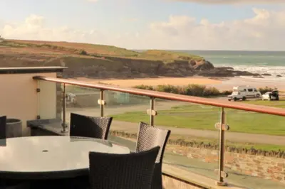 a balcony with a table and chairs and a view of the beach at Contemporary beachside apartment in St Merryn