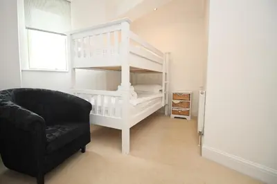 a living room with a black chair and a bunk bed at Contemporary beachside apartment in St Merryn