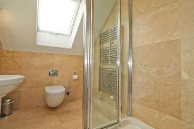 a bathroom with a shower and a toilet and a sink at Contemporary beachside apartment in St Merryn