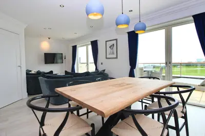 a dining room with a wooden table and chairs at Contemporary beachside apartment in St Merryn