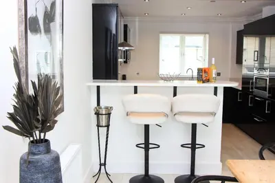 a kitchen with black and white counters and stools at Contemporary beachside apartment in St Merryn