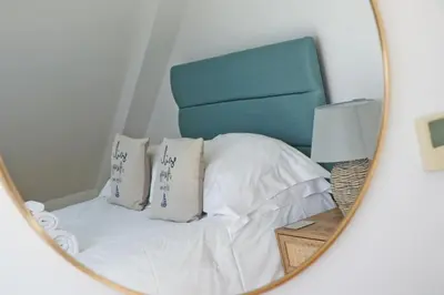 a bedroom with a bed with a blue headboard and a mirror at 50m FROM THE BEACH, dogs welcome in St Merryn